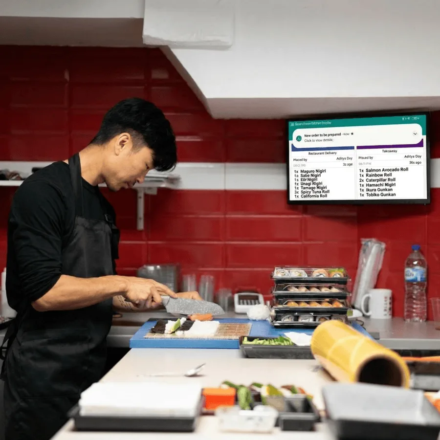 Kitchen cook working next to a RestroGreen Kitchen Display System screen