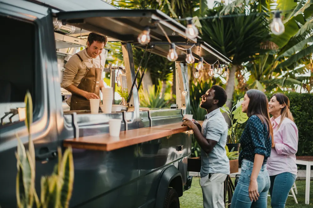Food cart vendor handing food to a customer and taking payment on a RestroGreen POS device